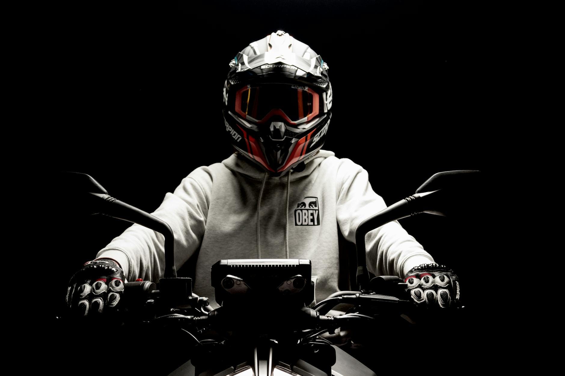 Motocyklista w kasku i rękawicach jedzie na tle ciemnego tła