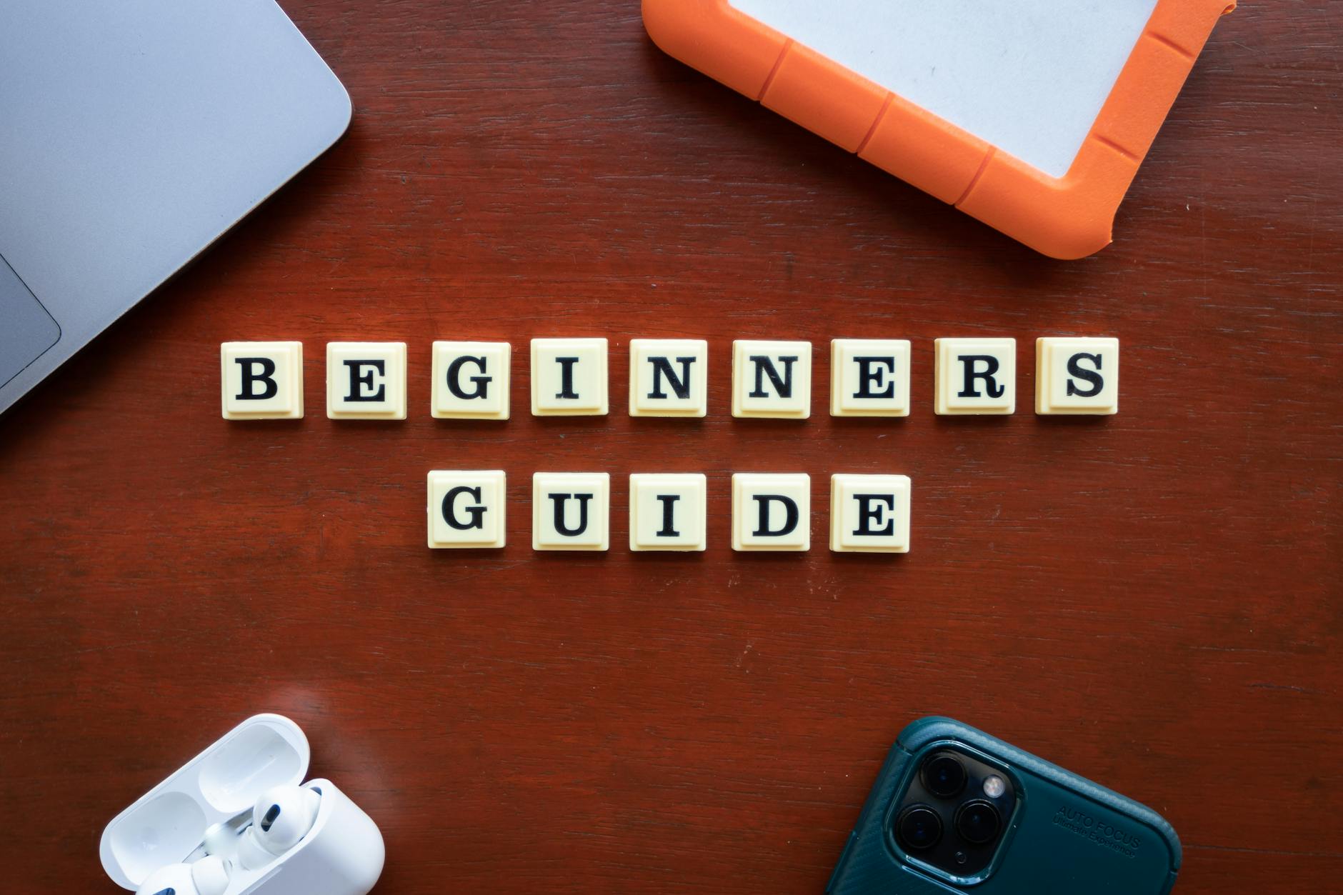 Gadżety podróżnika ułożone na drewnianym stole obok napisu Beginners Guide