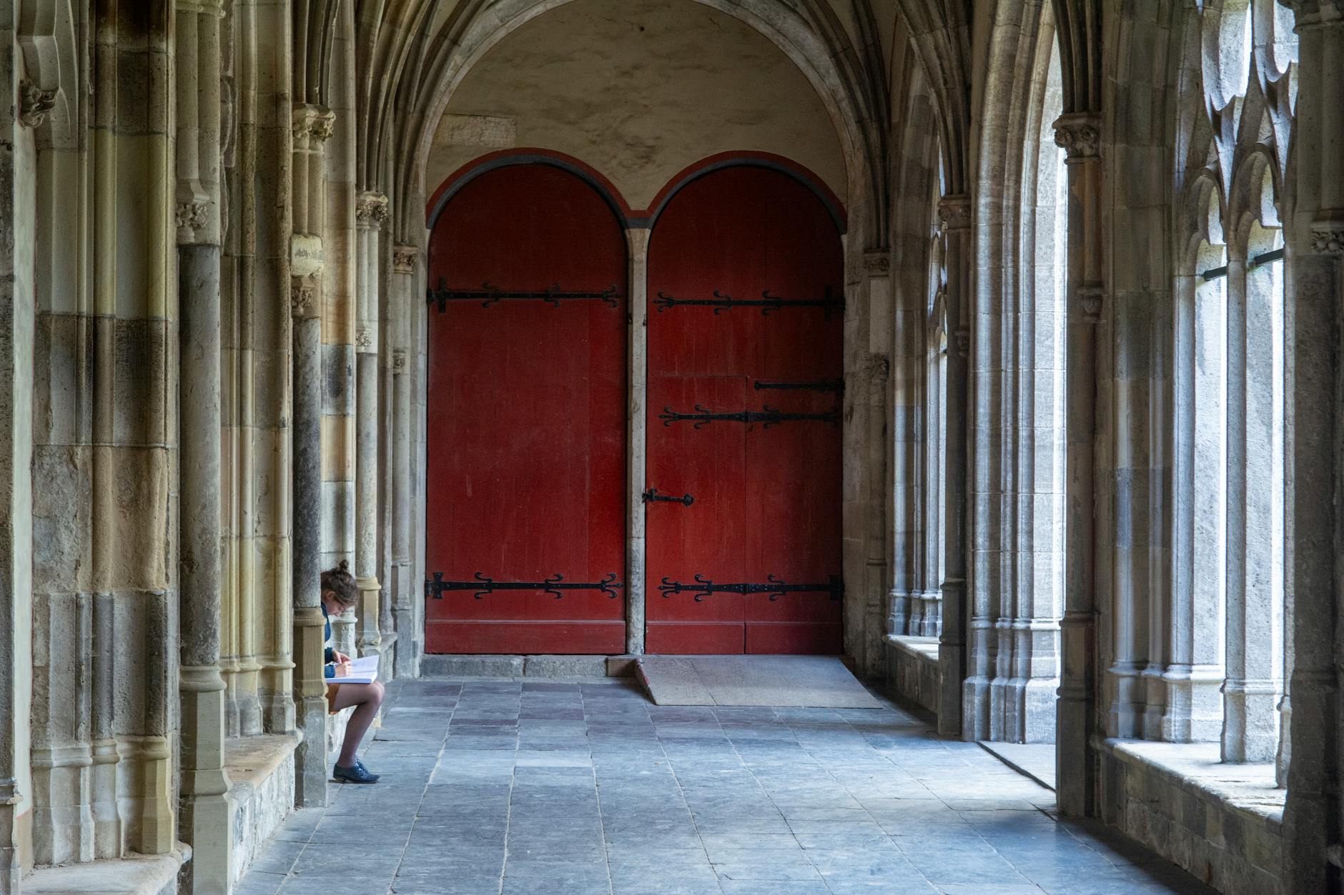 Gotycki krużganek w Utrechcie z czerwonymi drzwiami i kamiennymi arkadami