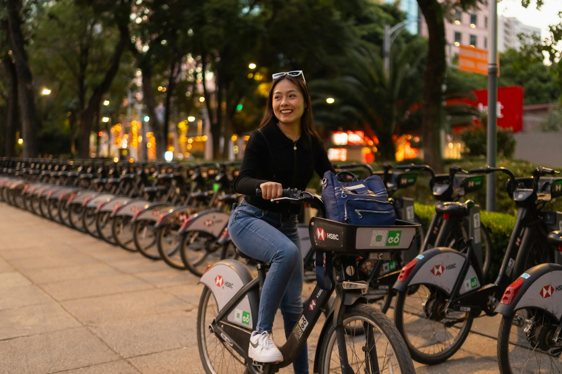 Kobieta na rowerze miejskim o zmierzchu na ulicy dużego miasta