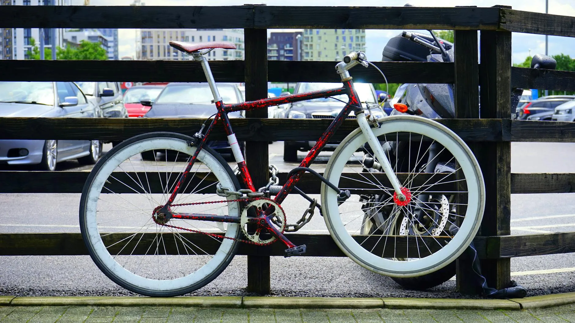 Rower przypięty do drewnianej barierki na parkingu w centrum miasta