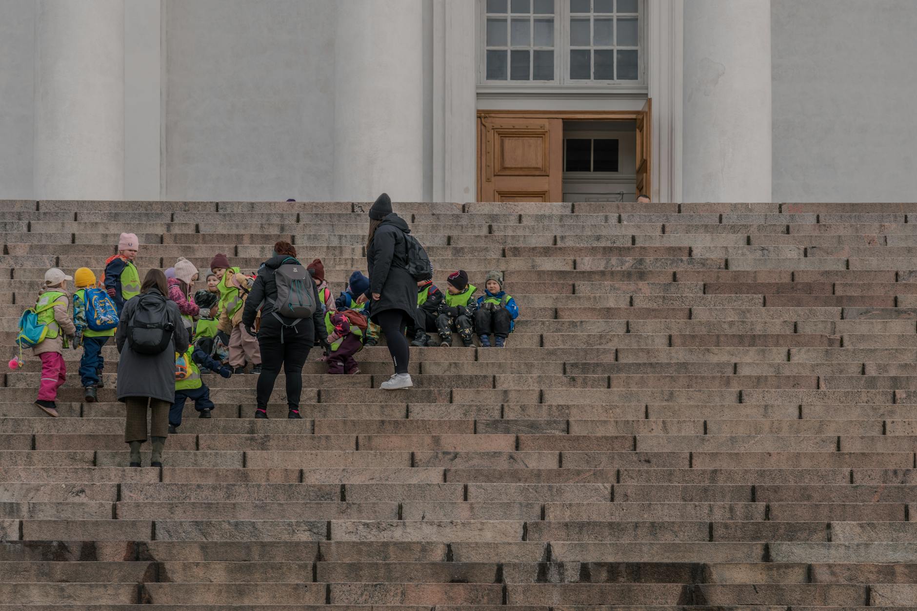 Dzieci z opiekunami na schodach katedry podczas zimowej wycieczki