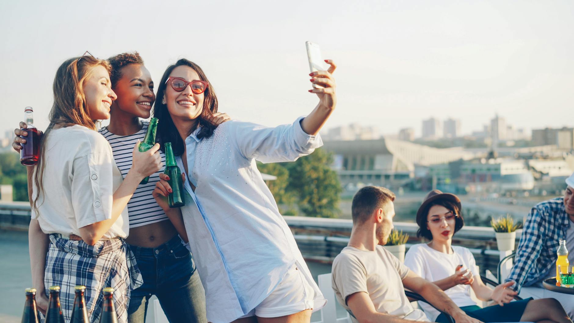 Grupa znajomych robi selfie na imprezie na dachu z widokiem na miasto