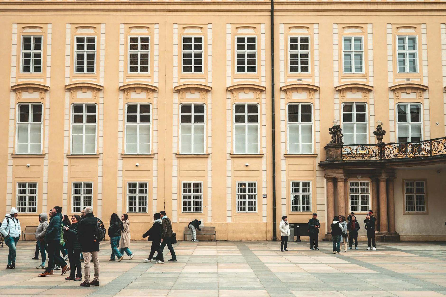 Turyści spacerują po historycznym dziedzińcu w słoneczny dzień