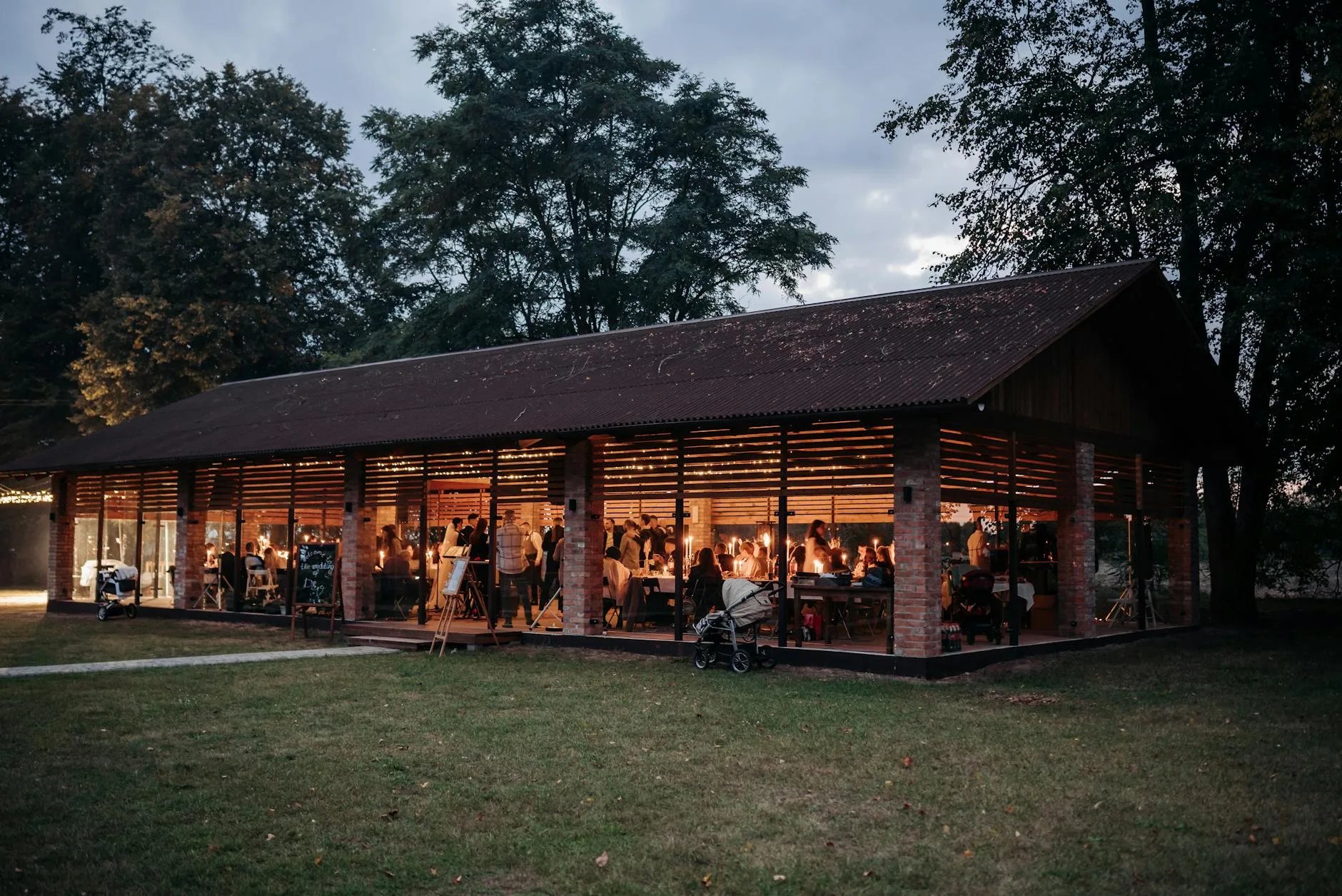 Wieczorna sala weselna w szklanym pawilonie wśród drzew