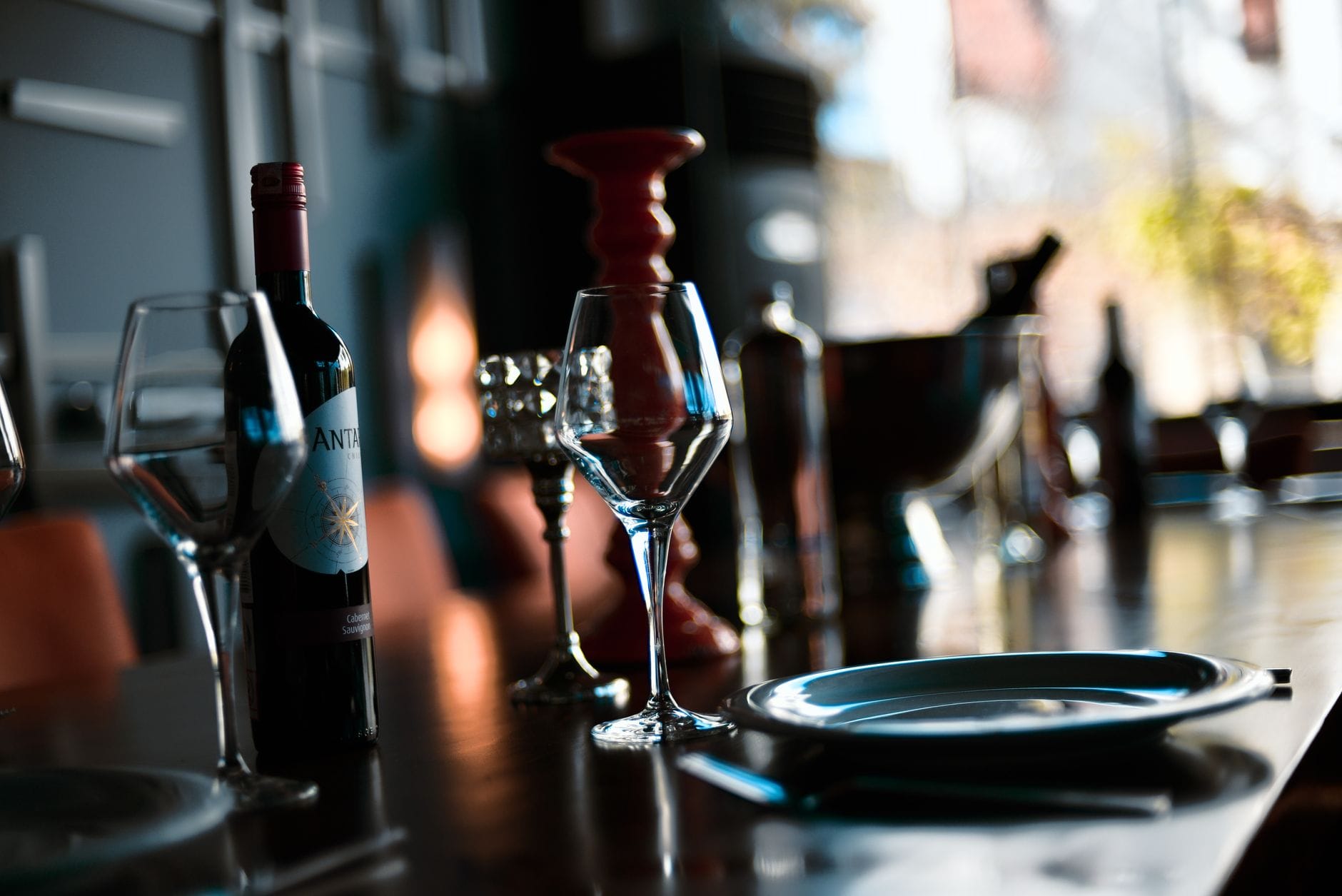 Eleganckie kieliszki i butelka wina w nastrojowym świetle restauracji