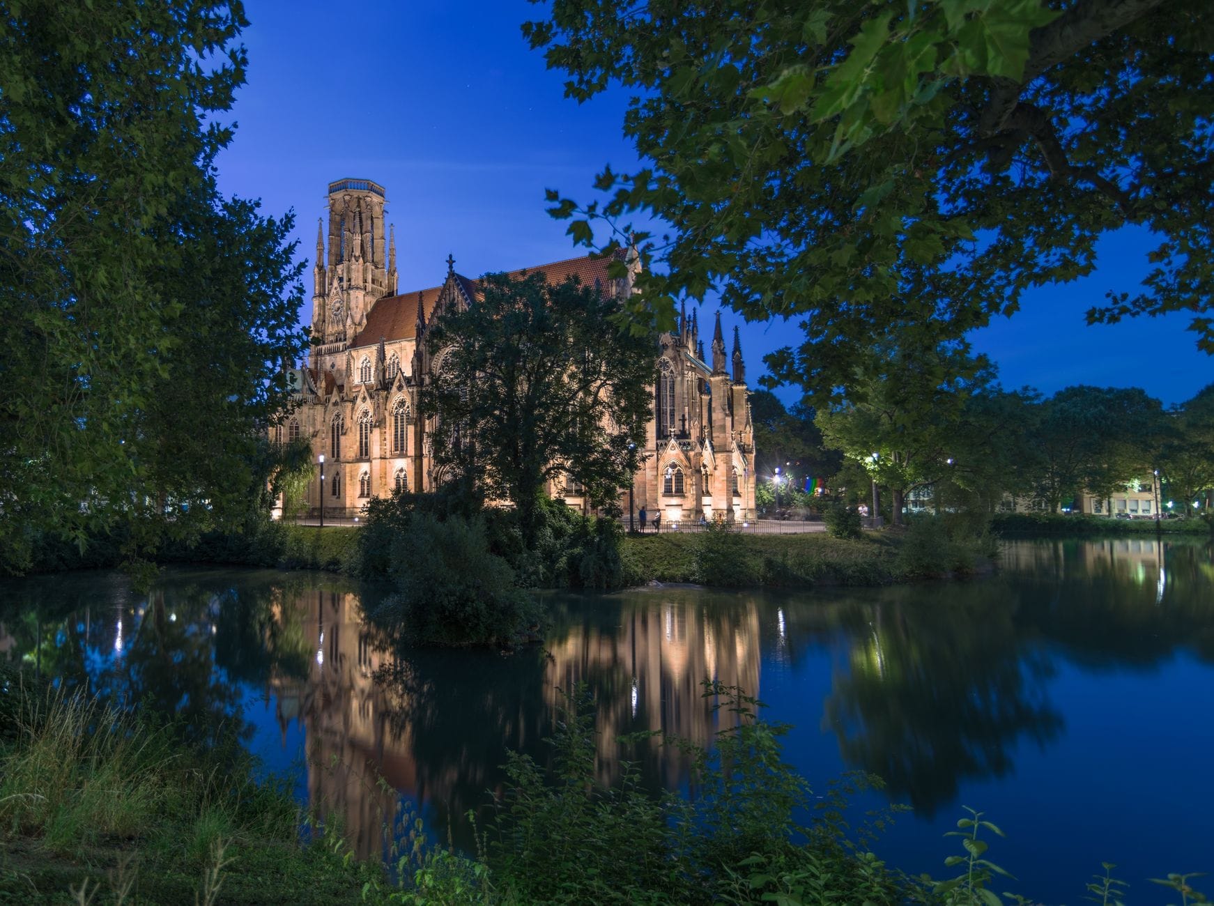 Nocne odbicie oświetlonego kościoła nad spokojnym jeziorem