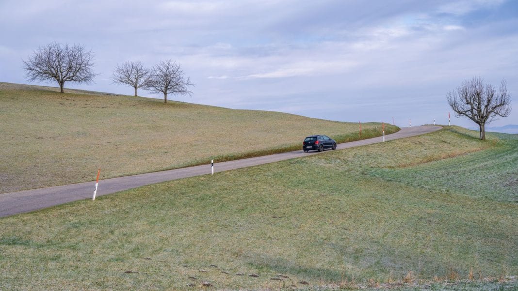 Samochód na krętej wiejskiej drodze wśród oszronionych pól