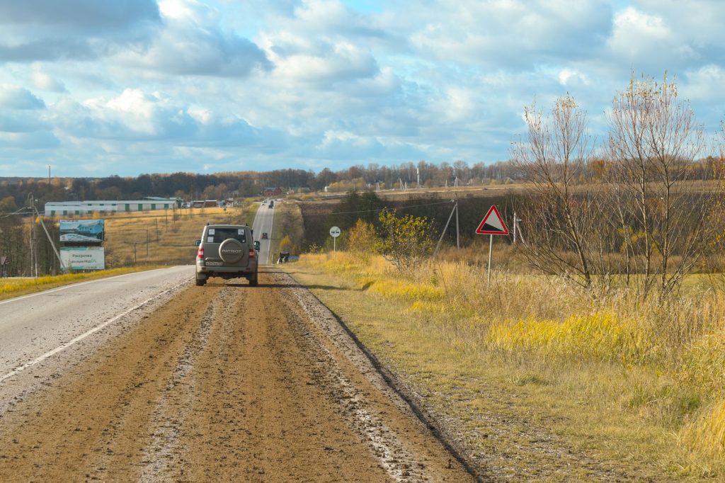 Samochód na wiejskiej drodze wśród jesiennych pól